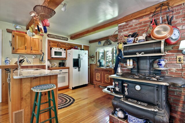 5100 Rte 100, Plymouth, VT 05056 - kitchen with white appliances, a sink, light wood-style floors, beam ceiling, and light stone counters