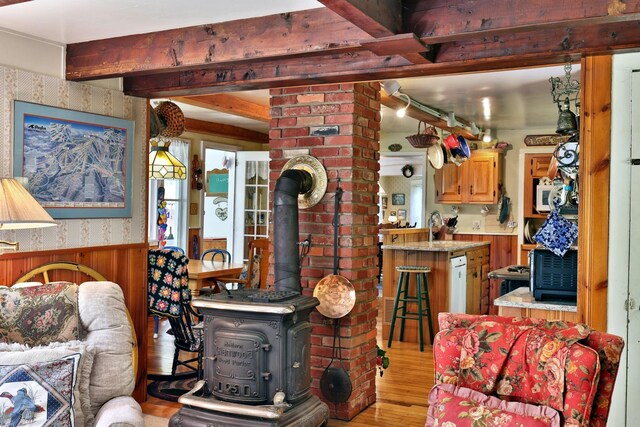 5100 Rte 100, Plymouth, VT 05056 - living area with a wood stove, wood finished floors, wallpapered walls, wainscoting, and beamed ceiling