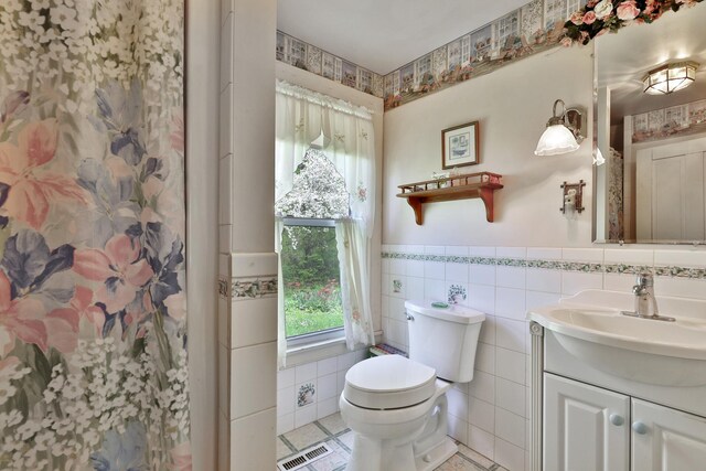 5100 Rte 100, Plymouth, VT 05056 - full bathroom featuring toilet, tile walls, vanity, a wainscoted wall, and plenty of natural light