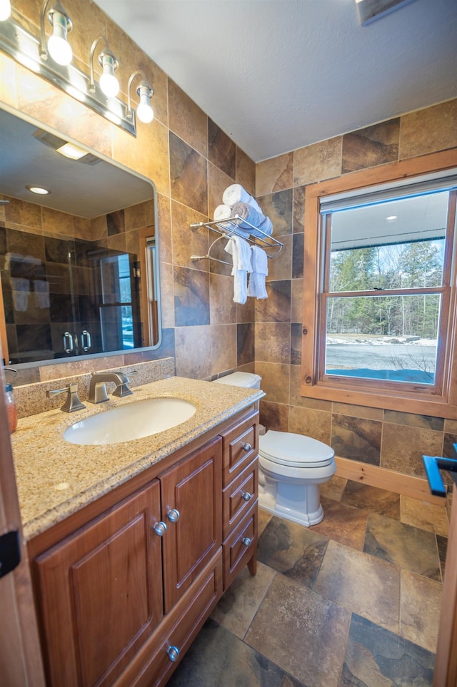 15 Spring Hill Rd, Dover, VT 05356 - bathroom with tile walls, a stall shower, vanity, toilet, and stone finish floors
