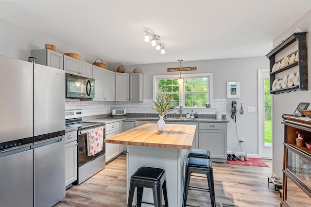 312 Browns Trce, Jericho, VT 05465 - kitchen featuring appliances with stainless steel finishes, butcher block counters, a kitchen bar, backsplash, and light wood-style flooring