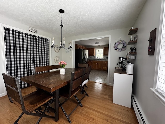 10 Irving Dr, Weare, NH 03281 - dining area featuring a chandelier, light wood finished floors, baseboard heating, and a textured ceiling