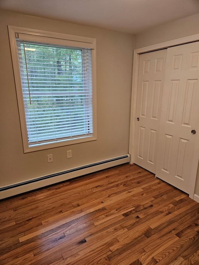 10 Irving Dr, Weare, NH 03281 - unfurnished bedroom featuring baseboard heating, multiple windows, a closet, and wood finished floors
