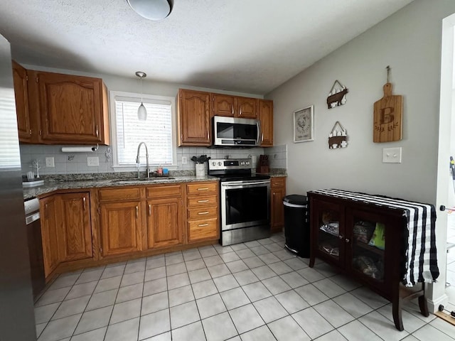 10 Irving Dr, Weare, NH 03281 - kitchen featuring appliances with stainless steel finishes, a sink, brown cabinetry, decorative backsplash, and stone counters