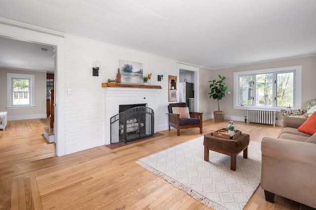 354 Dover Point Rd, Dover, NH 03820 - living area with radiator heating unit, a brick fireplace, light wood finished floors, baseboards, and ornamental molding