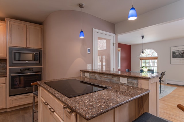 31 Plumley Ave, Ludlow, VT 05149 - kitchen with stainless steel oven, built in microwave, black electric stovetop, a kitchen breakfast bar, and wood finished floors