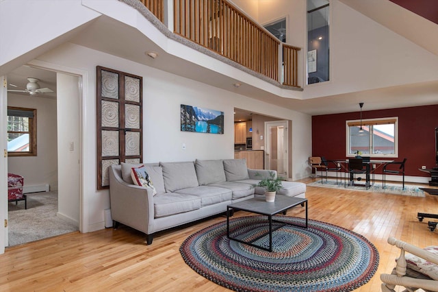 31 Plumley Ave, Ludlow, VT 05149 - living room featuring light wood-style floors, a high ceiling, a ceiling fan, a baseboard heating unit, and baseboards