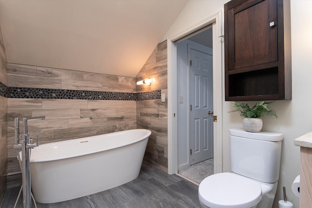 31 Plumley Ave, Ludlow, VT 05149 - bathroom featuring lofted ceiling, a freestanding tub, tile walls, and toilet