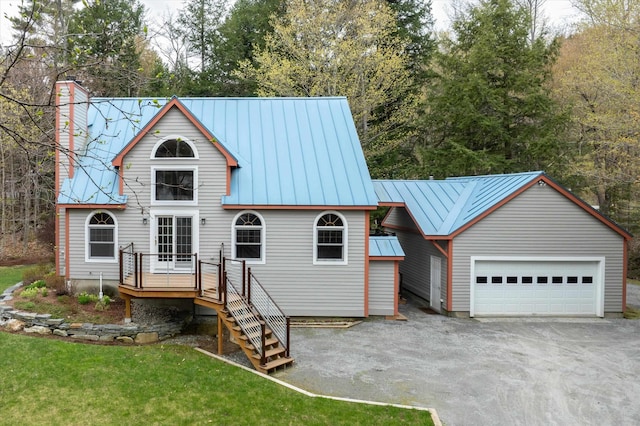 31 Plumley Ave, Ludlow, VT 05149 - view of front facade featuring a standing seam roof, a wooden deck, a chimney, a garage, and metal roof