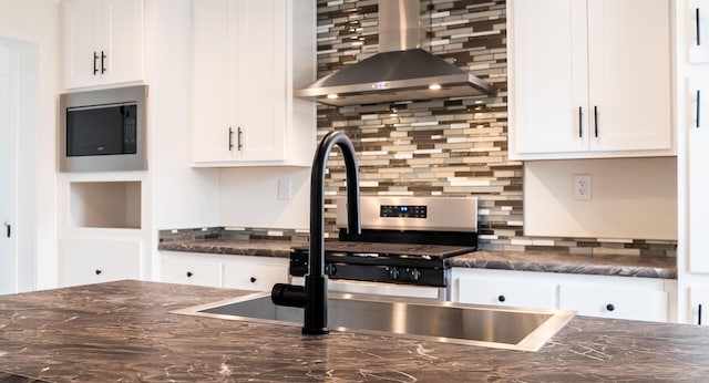 26 Deerfield Ct, Rochester, NH 03868 - kitchen with wall chimney exhaust hood, stainless steel microwave, white cabinetry, backsplash, and dark stone countertops