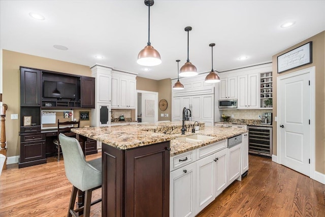 72 Settlers Ct, Bedford, NH 03110 - kitchen with wine cooler, stainless steel microwave, a sink, white cabinets, and backsplash