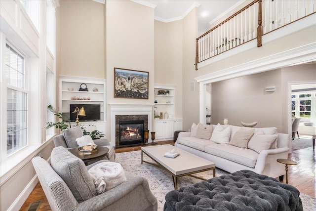 72 Settlers Ct, Bedford, NH 03110 - living area featuring a towering ceiling, wood finished floors, baseboards, built in shelves, and ornamental molding