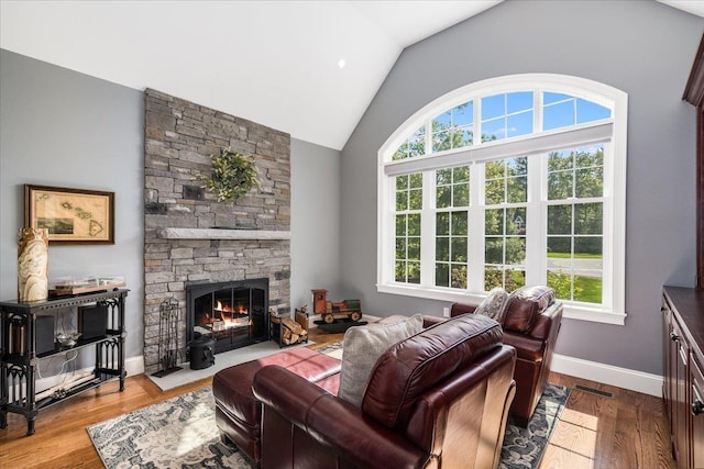 72 Settlers Ct, Bedford, NH 03110 - living area featuring vaulted ceiling, plenty of natural light, a stone fireplace, wood finished floors, and baseboards