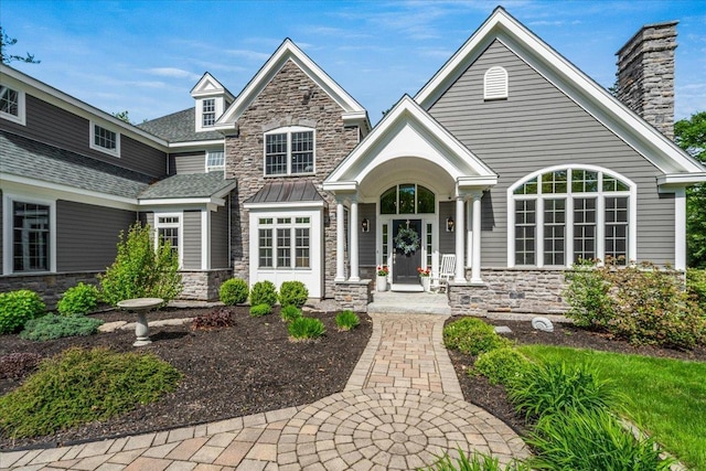72 Settlers Ct, Bedford, NH 03110 - view of front facade with stone siding, a chimney, and a shingled roof