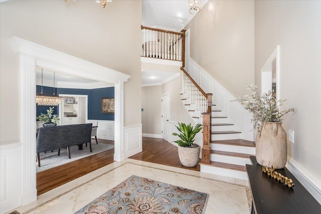 72 Settlers Ct, Bedford, NH 03110 - foyer entrance featuring marble tiled floors, ornamental molding, stairs, a wainscoted wall, and a decorative wall