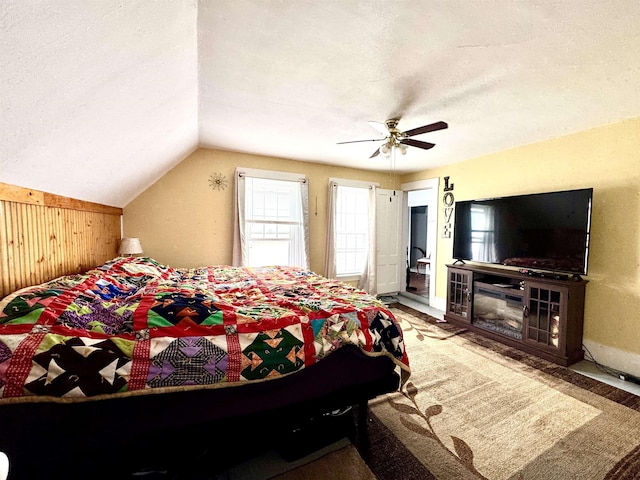 15 Park St, Colebrook, NH 03576 - carpeted bedroom featuring wooden walls, vaulted ceiling, a ceiling fan, and a textured ceiling