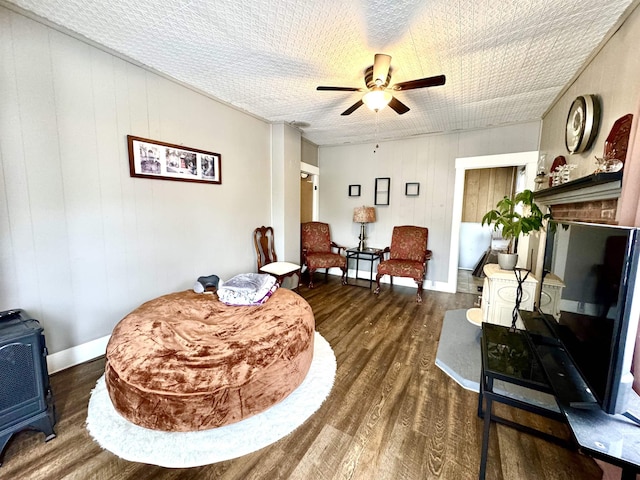 15 Park St, Colebrook, NH 03576 - sitting room featuring dark wood-style floors, a wood stove, a ceiling fan, and baseboards