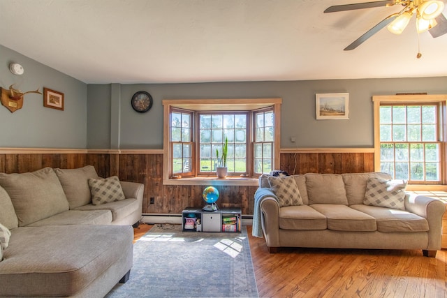 174 Andrews Rd, Holland, VT 05830 - living area featuring wainscoting, wooden walls, wood finished floors, a ceiling fan, and baseboard heating