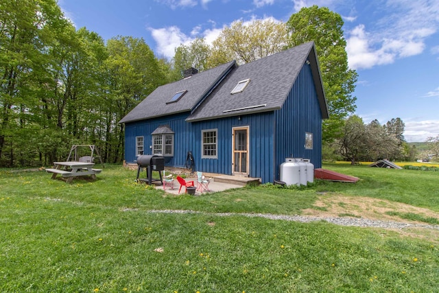 174 Andrews Rd, Holland, VT 05830 - back of property featuring a shingled roof, a chimney, a yard, a patio area, and board and batten siding