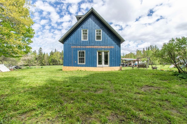 174 Andrews Rd, Holland, VT 05830 - rear view of house featuring board and batten siding, french doors, and a lawn