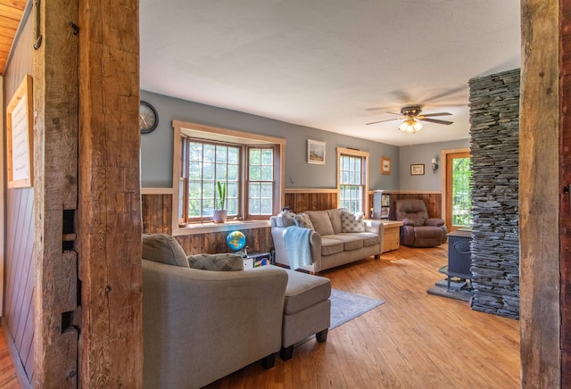 174 Andrews Rd, Holland, VT 05830 - living room featuring a wainscoted wall, wood finished floors, a ceiling fan, wooden walls, and ornate columns