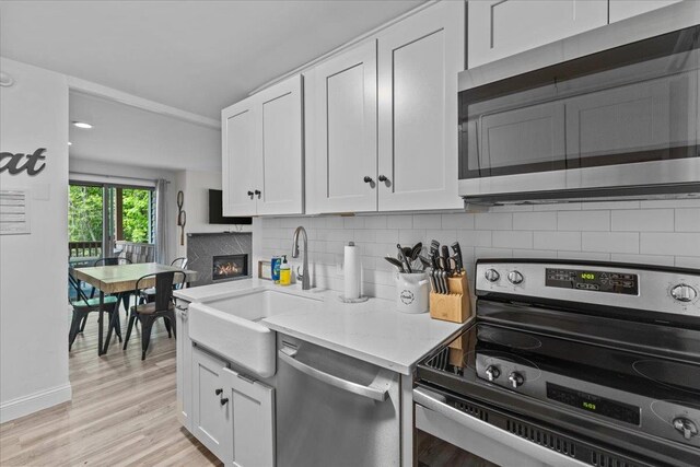 109 Mountainside Dr Unit G202, Stowe, VT 05672 - kitchen with appliances with stainless steel finishes, a sink, a glass covered fireplace, white cabinets, and recessed lighting