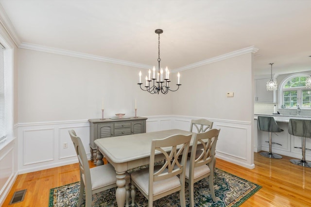 2 Cortland Rd, Milford, NH 03055 - dining room with a chandelier, light wood-style floors, ornamental molding, a decorative wall, and a wainscoted wall
