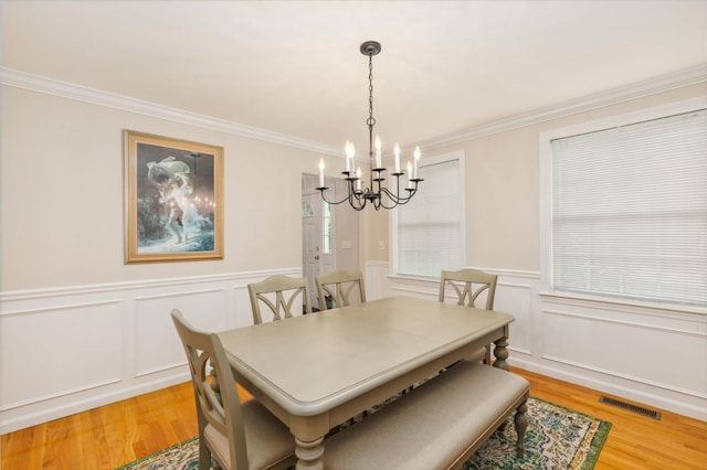 2 Cortland Rd, Milford, NH 03055 - dining area with a chandelier, light wood finished floors, ornamental molding, a decorative wall, and a wainscoted wall