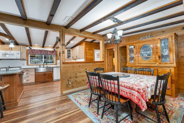 18 Mayflower Ln, Moultonborough, NH 03254 - dining area featuring wood walls, a chandelier, beam ceiling, and light wood-style floors