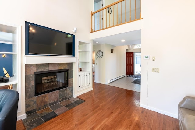 21 Hawk Ridge Rd, Meredith, NH 03253 - living area with baseboard heating, wood finished floors, built in features, baseboards, and a high ceiling