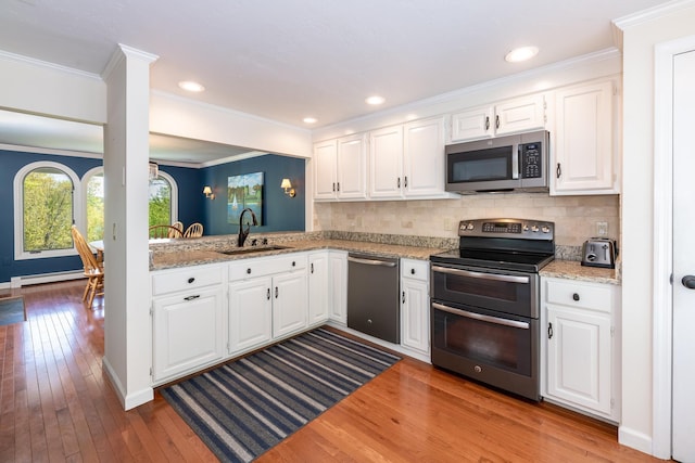 21 Hawk Ridge Rd, Meredith, NH 03253 - kitchen featuring stainless steel appliances, a sink, wood-type flooring, a baseboard radiator, and tasteful backsplash