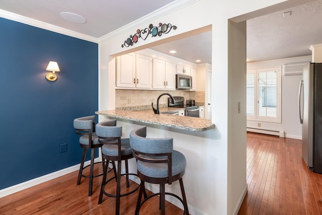 21 Hawk Ridge Rd, Meredith, NH 03253 - kitchen featuring stainless steel appliances, a baseboard radiator, baseboards, backsplash, and ornamental molding