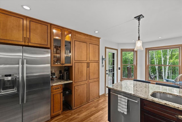 100 Maplewood Ave, Milton, VT 05468 - kitchen featuring appliances with stainless steel finishes, brown cabinetry, a sink, light wood-style floors, and recessed lighting