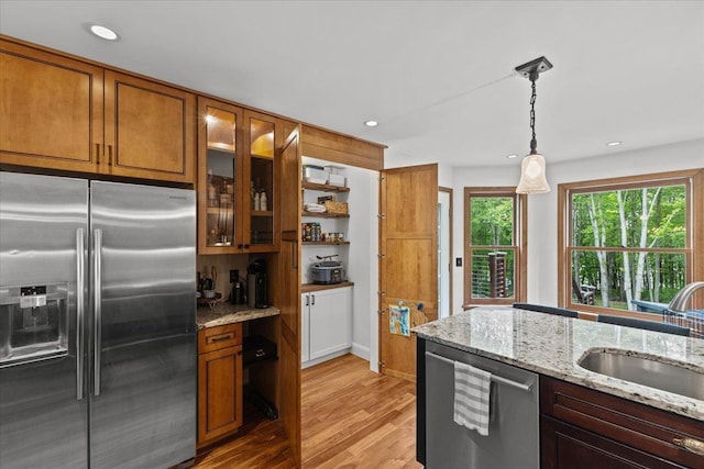 100 Maplewood Ave, Milton, VT 05468 - kitchen featuring appliances with stainless steel finishes, brown cabinetry, a sink, light wood-style flooring, and glass insert cabinets