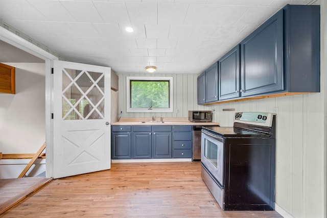 1572 Stowe Hollow Rd, Stowe, VT 05672 - kitchen with stainless steel appliances, blue cabinetry, a sink, light wood finished floors, and light countertops