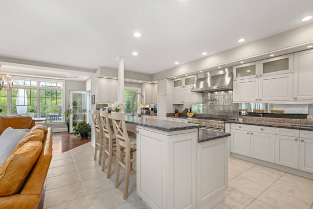 34 Orchard Hill Rd, Greenland, NH 03840 - kitchen with wall chimney range hood, light tile patterned floors, high end stainless steel range oven, plenty of natural light, and recessed lighting