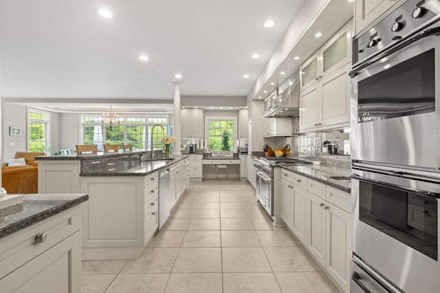 34 Orchard Hill Rd, Greenland, NH 03840 - kitchen featuring a sink, stainless steel appliances, wall chimney range hood, light tile patterned floors, and dark stone counters