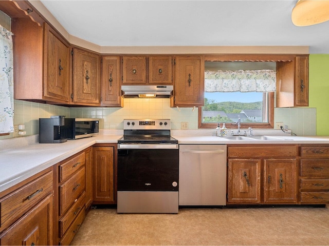 37 Dickinson Dr, Northfield, VT 05664 - kitchen featuring appliances with stainless steel finishes, under cabinet range hood, brown cabinetry, and a sink