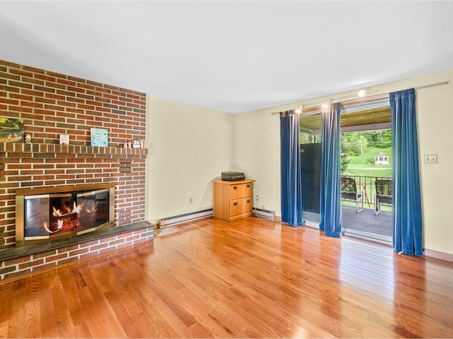 37 Dickinson Dr, Northfield, VT 05664 - unfurnished living room featuring baseboard heating, wood finished floors, a baseboard radiator, and a brick fireplace