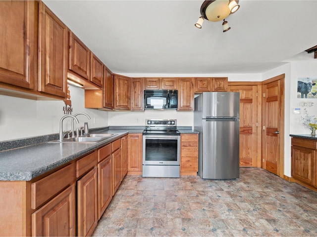 183 Morrie Rd, Washington, VT 05675 - kitchen with stainless steel appliances, a sink, stone finish floors, dark countertops, and brown cabinetry