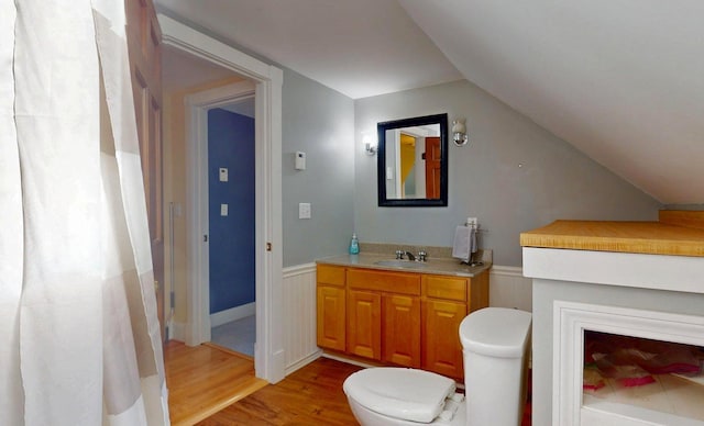 825 S End Rd, North Hero, VT 05457 - full bathroom with wood finished floors, toilet, vanity, a wainscoted wall, and lofted ceiling