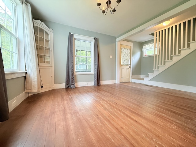 19 Gambier St, Claremont, NH 03743 - spare room featuring a chandelier, stairway, hardwood / wood-style floors, and healthy amount of natural light