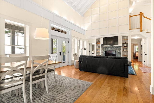 8 Wisteria Ln, Eliot, ME 03903 - living room featuring high vaulted ceiling, light wood finished floors, french doors, and a stone fireplace