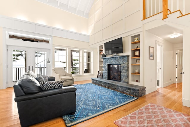 8 Wisteria Ln, Eliot, ME 03903 - living area featuring a towering ceiling, wood finished floors, a stone fireplace, built in features, and french doors