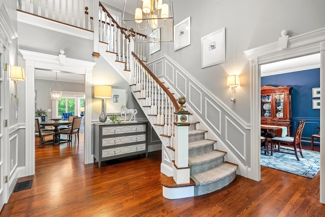 52 Hardy Rd, Bedford, NH 03110 - stairway with a chandelier, wood finished floors, a decorative wall, a high ceiling, and wainscoting