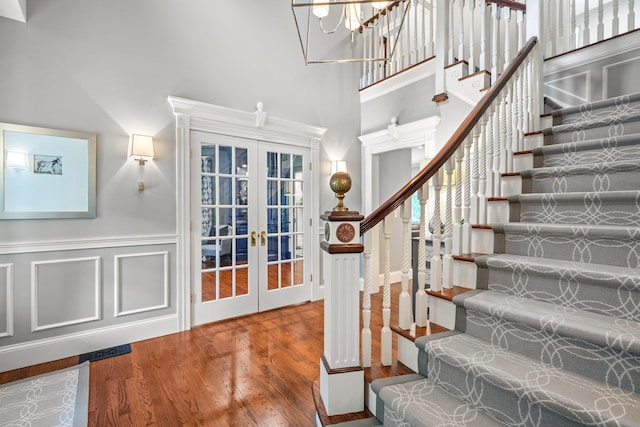 52 Hardy Rd, Bedford, NH 03110 - stairs with french doors, wood finished floors, a towering ceiling, a chandelier, and wainscoting