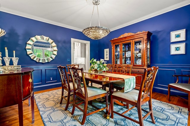 52 Hardy Rd, Bedford, NH 03110 - dining space featuring ornamental molding, a decorative wall, a chandelier, wood finished floors, and a wainscoted wall