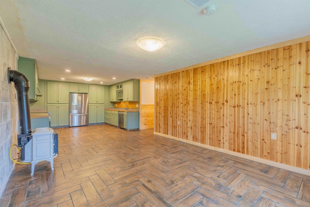 122 Flagg Rd, Rochester, NH 03839 - unfurnished living room with a wood stove, wooden walls, baseboards, a sink, and a textured ceiling
