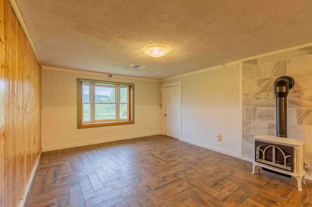 122 Flagg Rd, Rochester, NH 03839 - unfurnished living room with a textured ceiling, a wood stove, crown molding, a wainscoted wall, and baseboards