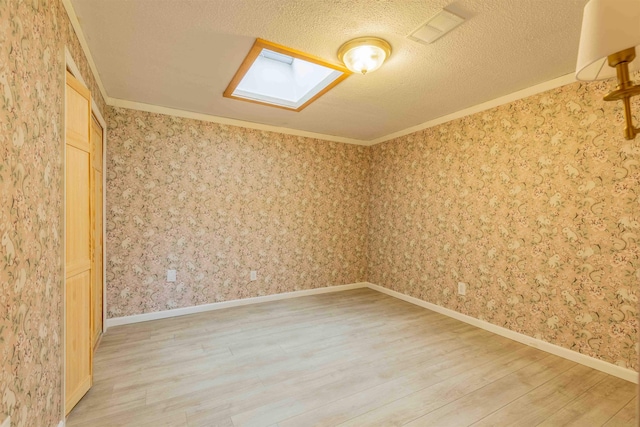122 Flagg Rd, Rochester, NH 03839 - spare room with light wood-style flooring, a skylight, crown molding, and a textured ceiling